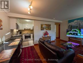 Toronto (High Park North) multi-family for rent - A living room with a brown leather couch and a coffee table with a vase of flowers on it.