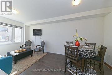Cambridge townhouse for rent - A living room with a black couch, a chair, a small table with a vase of flowers, and a television.