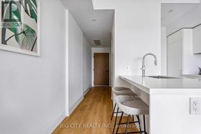 Toronto (Thorncliffe Park) condo for rent - A white kitchen with a bar stool and a painting on the wall.