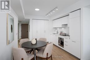 Toronto (Thorncliffe Park) condo for rent - A modern kitchen with white cabinets and a black table with a vase on it.