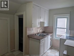 Windsor duplex for rent - A kitchen with white cabinets and a tiled backsplash.