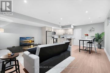 Toronto (Oakridge) apartment for rent - A modern living room with a black couch and a painting on the wall.