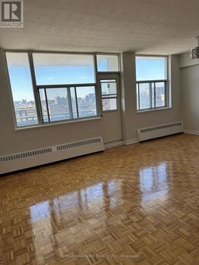 Toronto (Ionview) condo for rent - A large empty room with wooden floors and windows overlooking a city.