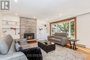 Oakville (Br Bronte) apartment for rent - A living room with a grey leather couch and a stone fireplace.