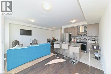 Cambridge townhouse for rent - A blue couch is in the middle of a living room with a television and a kitchen area in the background.