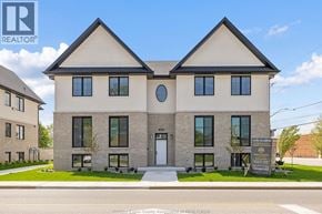 Tecumseh apartment for rent - A two-story house with a large front porch and a sign that says "The Woods".