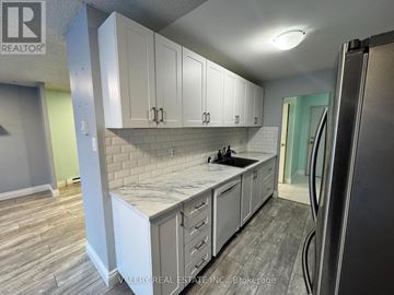 Kitchener condo for rent - A kitchen with white cabinets and a marble countertop.
