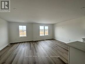 Niagara Falls (Brown) townhouse for rent - A spacious room with wood flooring and two windows.