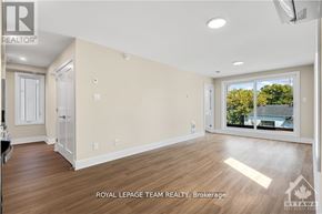 Ottawa apartment for rent - A spacious room with wooden flooring and a large window overlooking a backyard.