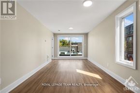 Ottawa apartment for rent - A spacious room with wooden flooring and a large window overlooking a balcony.