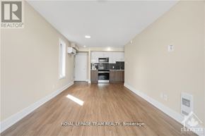 Ottawa apartment for rent - A spacious room with wooden flooring and a kitchen area in the background.
