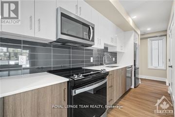 Ottawa apartment for rent - A modern kitchen with a stove top oven and microwave above it.