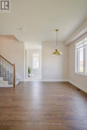 Ottawa apartment for rent - A large, empty room with a wooden floor and a staircase with a metal railing.
