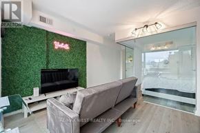 Toronto (Annex) condo for rent - A living room with a couch, a glass table, and a green wall with a TV on it.
