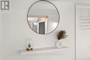 Toronto (Annex) condo for rent - A round mirror hangs on a wall above a shelf with a plant and a vase on it.