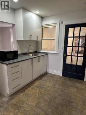 Hamilton apartment for rent - A kitchen with white cabinets and a black door.