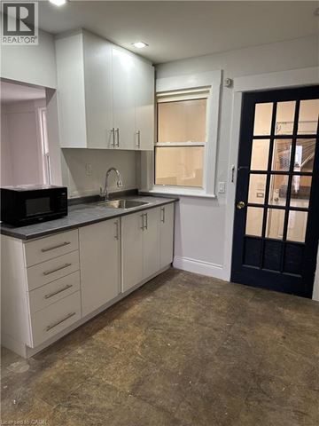 Hamilton apartment for rent - A kitchen with white cabinets and a black door.
