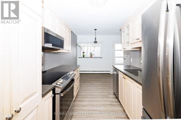 St. Catharines (Downtown) condo for rent - A kitchen with a stove top oven and a refrigerator.
