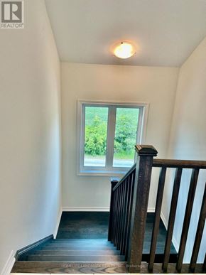 Markham (Victoria Square) townhouse for rent - A staircase with a wooden railing leads to a window with a view of greenery outside.