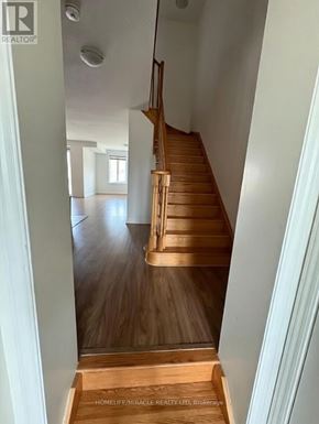 Tillsonburg townhouse for rent - A wooden staircase leads up to a bright room.