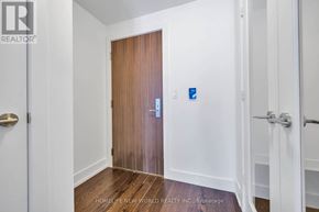 Toronto (Annex) condo for rent - A hallway with a wooden door and a blue handicap sign.