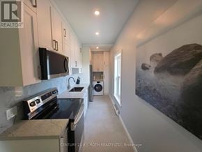Orillia multi-family for rent - A kitchen with a stove top oven and a microwave on the counter.