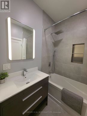 Orillia multi-family for rent - A bathroom with a sink, mirror, and bathtub.