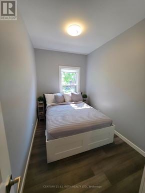 Orillia multi-family for rent - A bedroom with a bed, nightstand, and window.