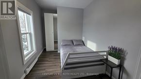 Orillia multi-family for rent - A bedroom with a bed, nightstand, and window.