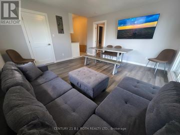 Orillia multi-family for rent - A living room with grey couches and a painting on the wall.
