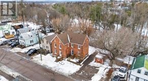 Pembroke multi-family for rent - A red brick house with a brown roof in the middle of a snowy street.