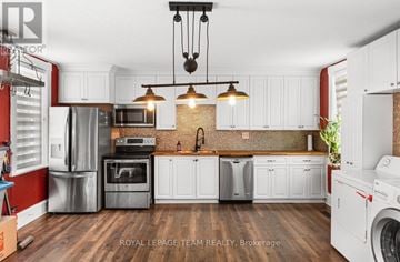 Pembroke multi-family for rent - A modern kitchen with white cabinets and a brick backsplash.