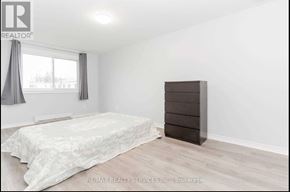 Oshawa (Lakeview) townhouse for rent - A bedroom with a bed, a dresser, and a window with curtains.