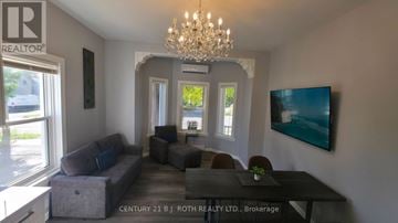Orillia multi-family for rent - A living room with a grey couch and a chandelier.
