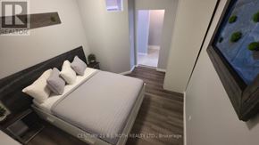 Orillia multi-family for rent - A bedroom with a bed, nightstand, and a painting on the wall.