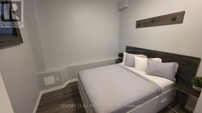 Orillia multi-family for rent - A bedroom with a bed, pillows, and a small plant on the nightstand.