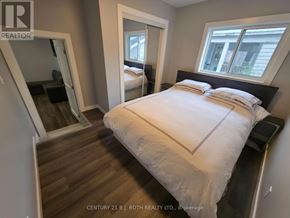 Orillia multi-family for rent - A bedroom with a large bed and a mirror on the wall.