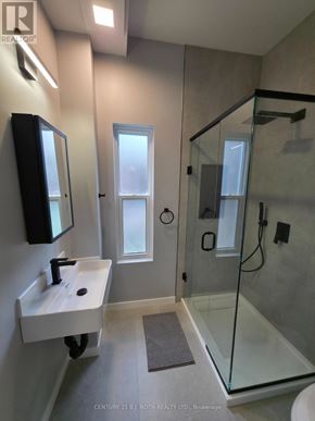 Orillia multi-family for rent - A bathroom with a sink, mirror, and shower.