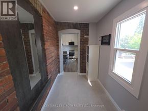 Orillia multi-family for rent - A hallway with a brick wall and a white refrigerator.