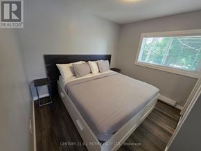 Orillia multi-family for rent - A bedroom with a bed, nightstand, and window.