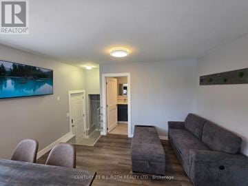 Orillia multi-family for rent - A living room with a grey couch and a television mounted on the wall.