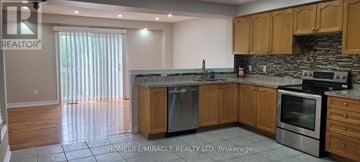 Brampton (Fletcher's Meadow) apartment for rent - A kitchen with wooden cabinets and a stone backsplash.