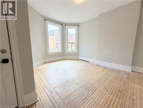 Hamilton apartment for rent - A room with wooden flooring and a window overlooking a building.