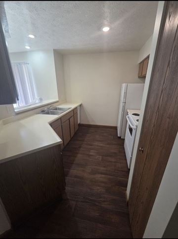 Wakarusa apartment for rent - A kitchen with a white fridge and wooden floors.