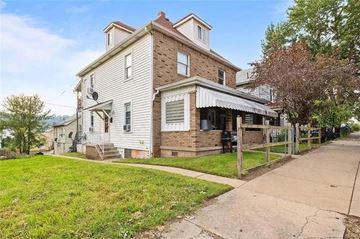 New Kensington apartment for rent - A two-story house with a brick facade and a covered porch.