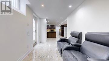 Markham (Cachet) apartment for rent - A spacious living room with a grey sofa and a kitchen in the background.