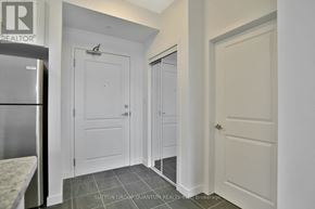 Hamilton (Stoney Creek) condo for rent - A kitchen with a refrigerator and a door on the left.