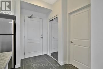 Hamilton (Stoney Creek) condo for rent - A kitchen with a refrigerator and a door on the left.