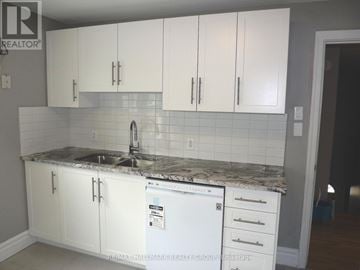 Ottawa fourplex for rent - A kitchen with white cabinets and a white fridge.