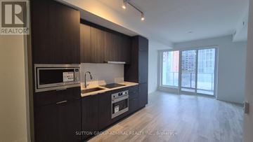 Toronto (Newtonbrook East) condo for rent - A kitchen with dark wood cabinets and a white countertop.